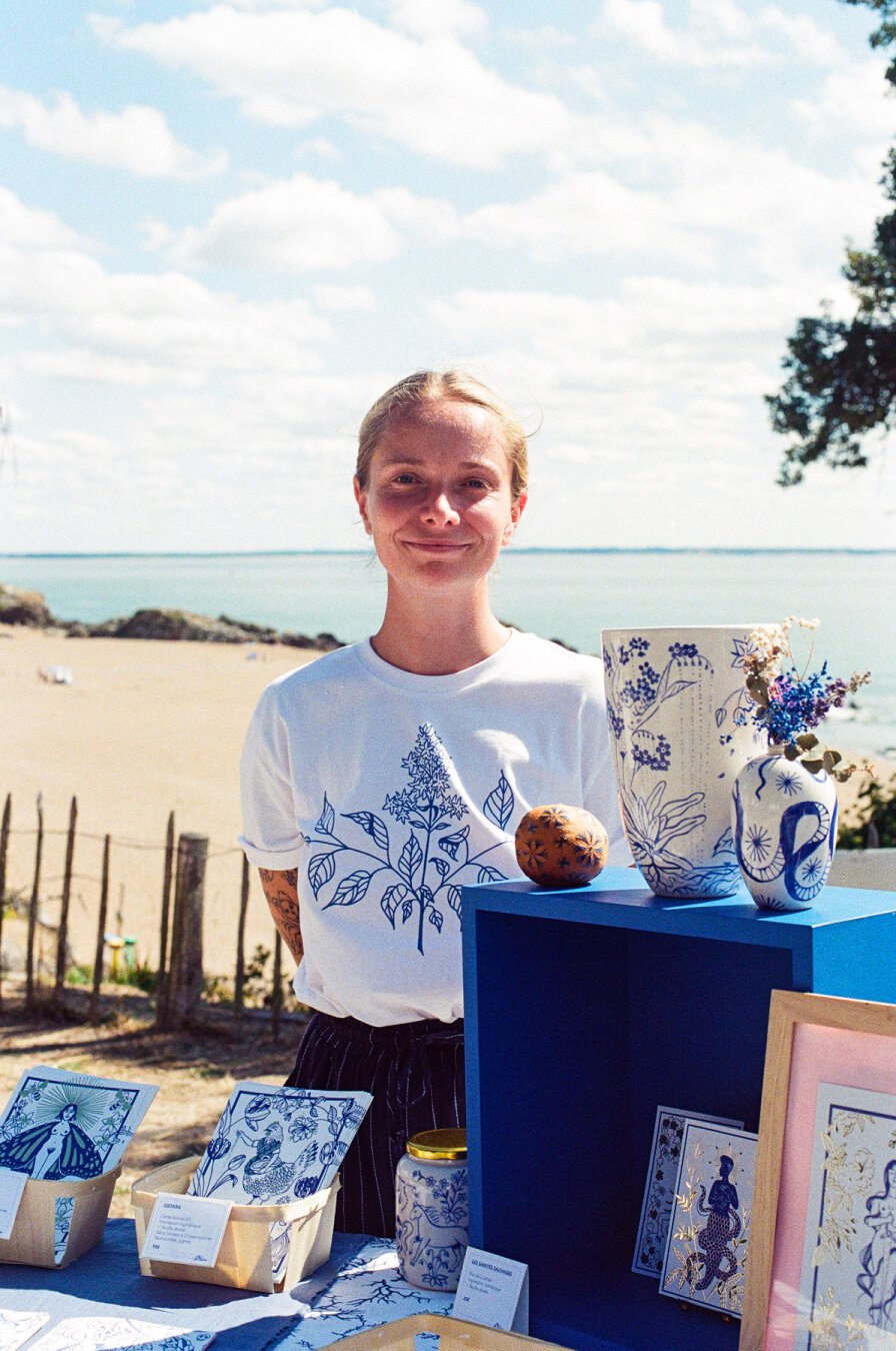 Une photo de moi entourée de mes productions, la plage et la mer en arrière plan