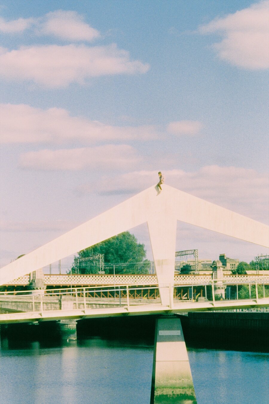 Colour photo of a bridge in Glasgow with a man sitting on it