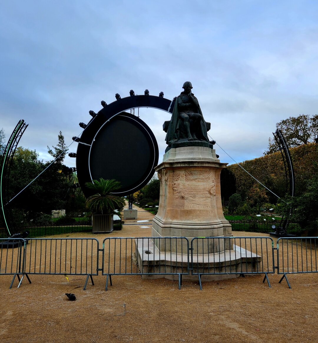 Lamarck statue at the Jardin des Plantes in Paris behind a temporary fence and with a circular structure being mounted behind