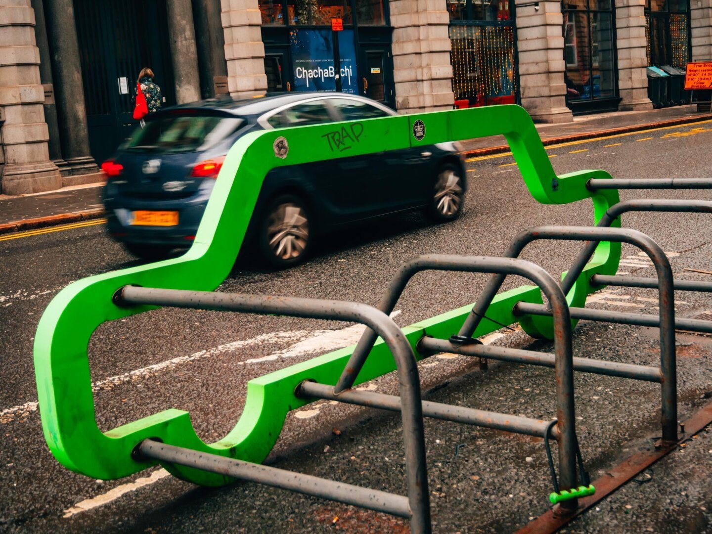 Green bike storage with car driving behind