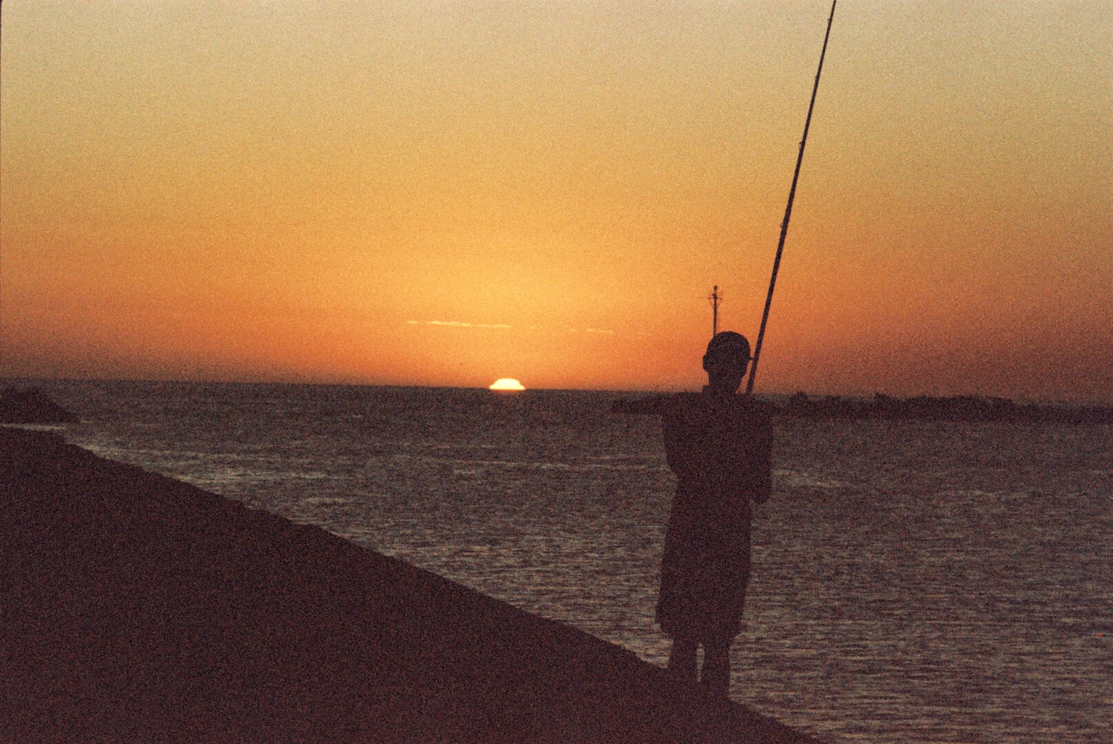 Un pescador contempla el atardecer en la Escollera Sarandí.