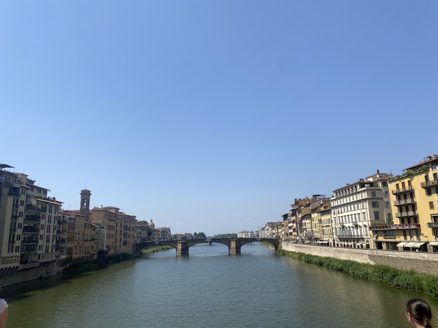 The image is of a small or medium pedestrian walkway bridge in Venice. The buildings line the waterway. The perspective is taken from another bridge.