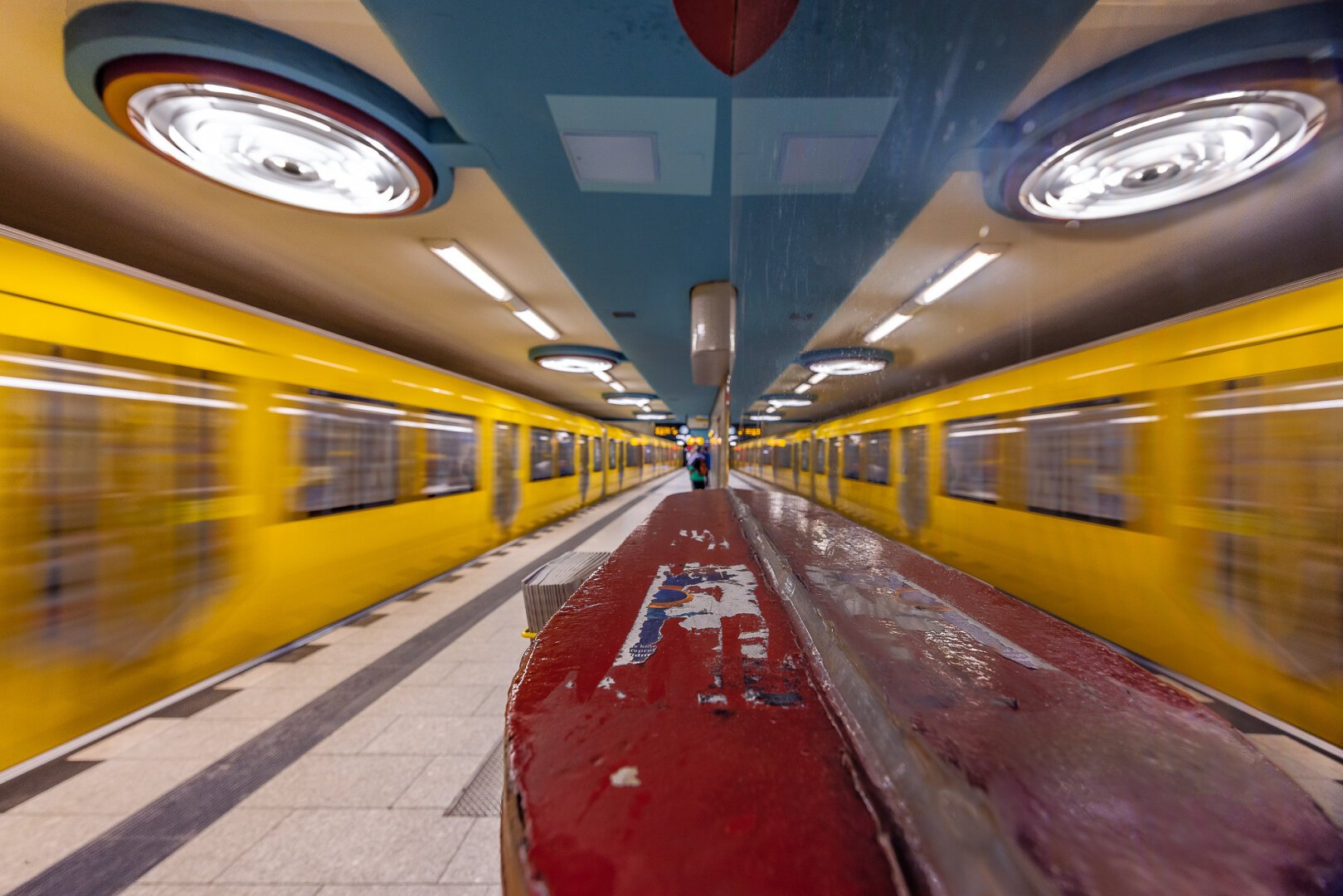 Long exposure reflexion shot in a glass panel at Nauener Platz U-Bahn Station in Berlin just when a yellow train enters the colourful station with huge round lamps on the ceiling. This composition creates a funny alien creature with two big eyes.