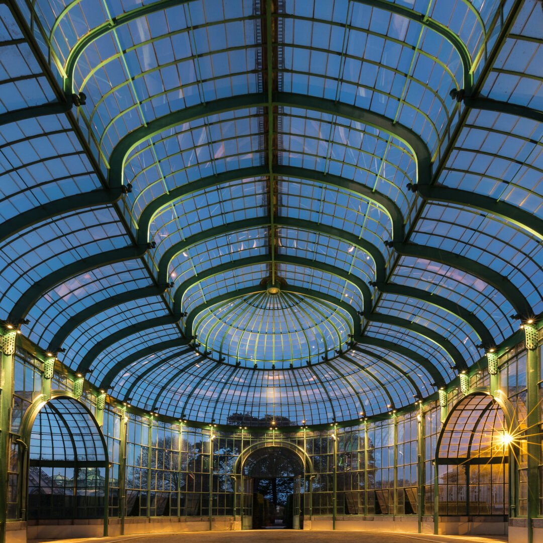 long exposure look-up shot at blue hour of the Theater Greenhouse at the Royal Greenhouses of Laeken, in Brussels, Belgium. The perspective accentuates the curves and leading lines of the remarkable glass ceiling of this building, which was built at the premises of the Art Nouveau movement in Brussels.