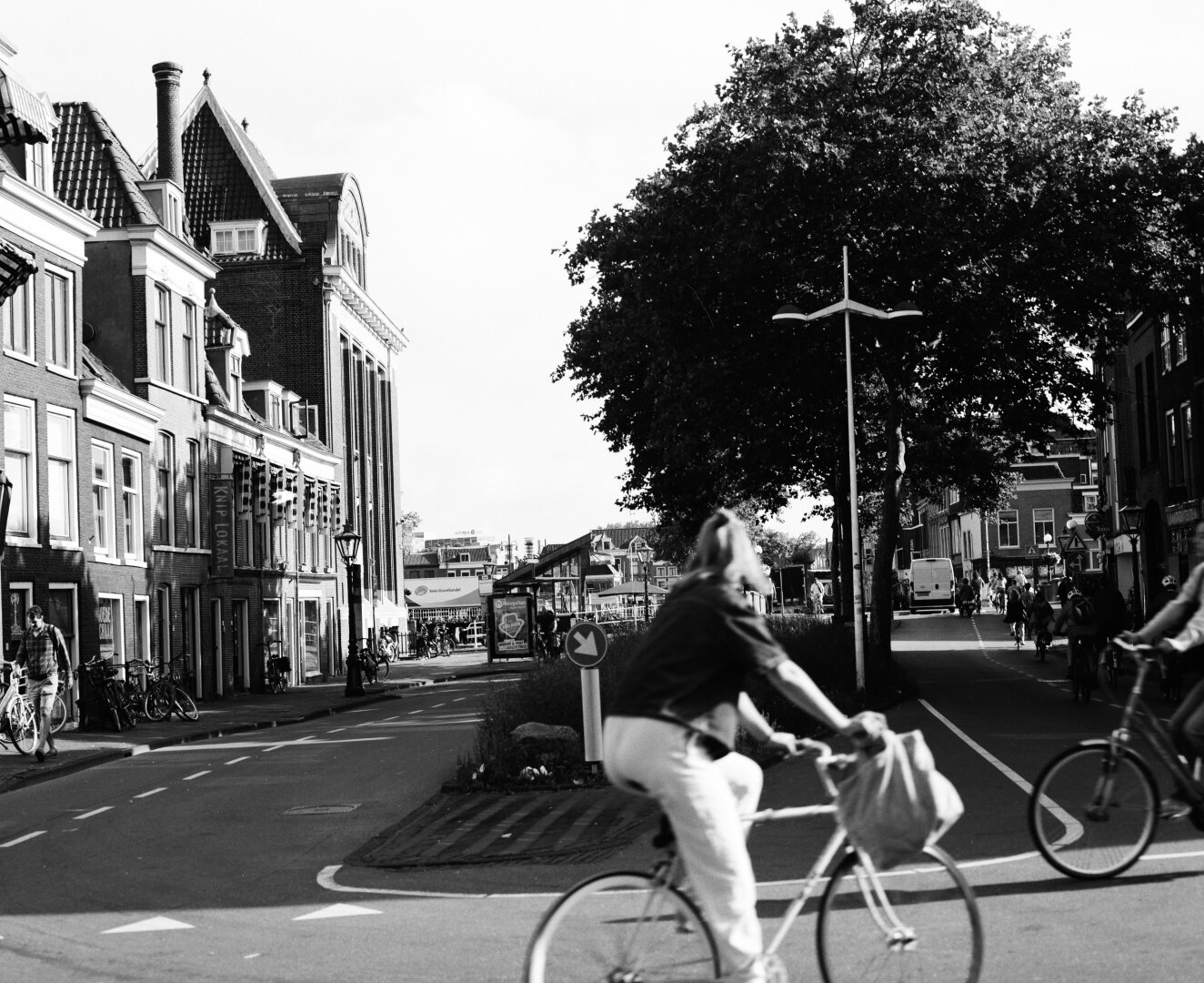 Candid black and white photo of bikers riding by on the streets of Leiden, Netherlands
