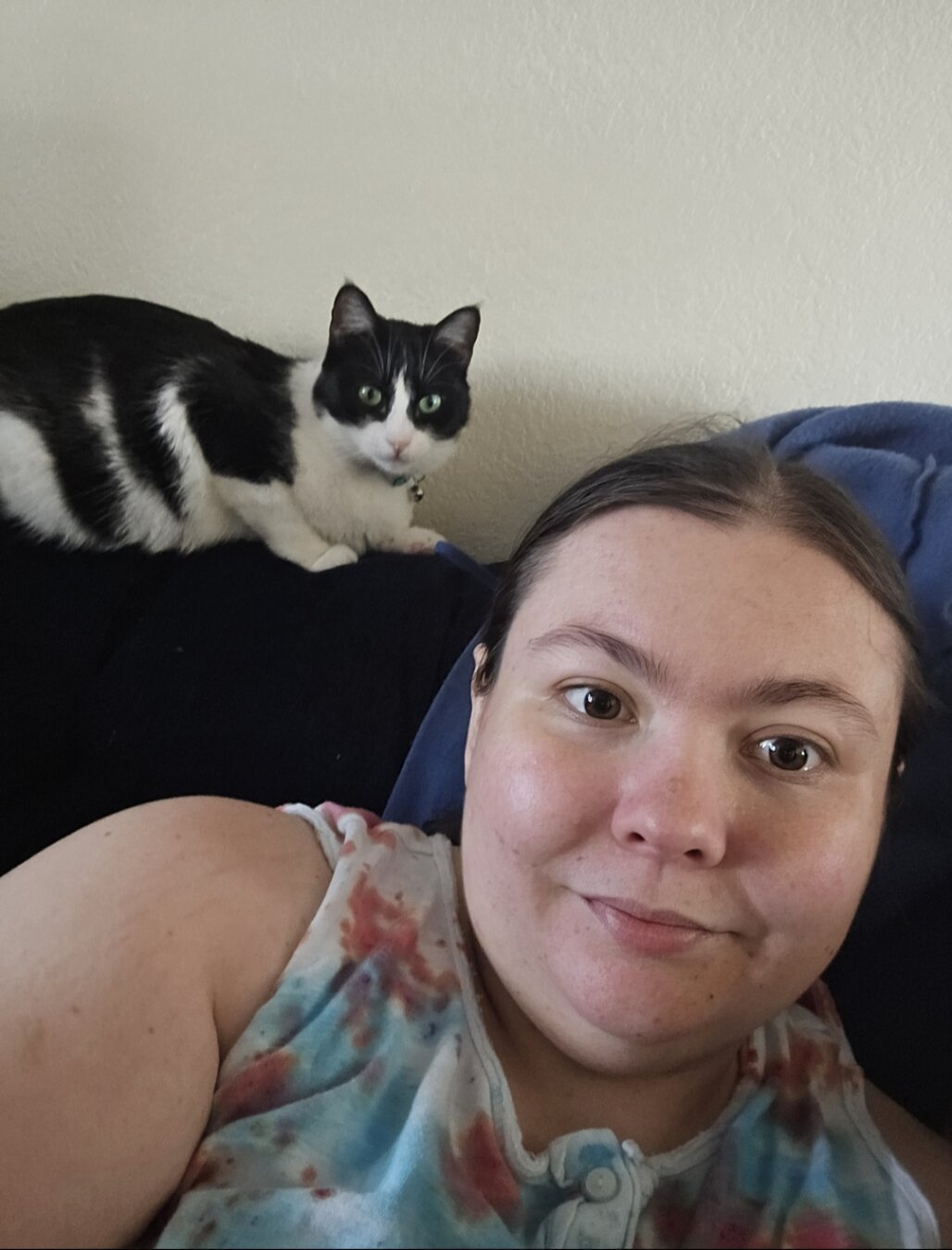 Woman sitting on couch with cat on top of couch
