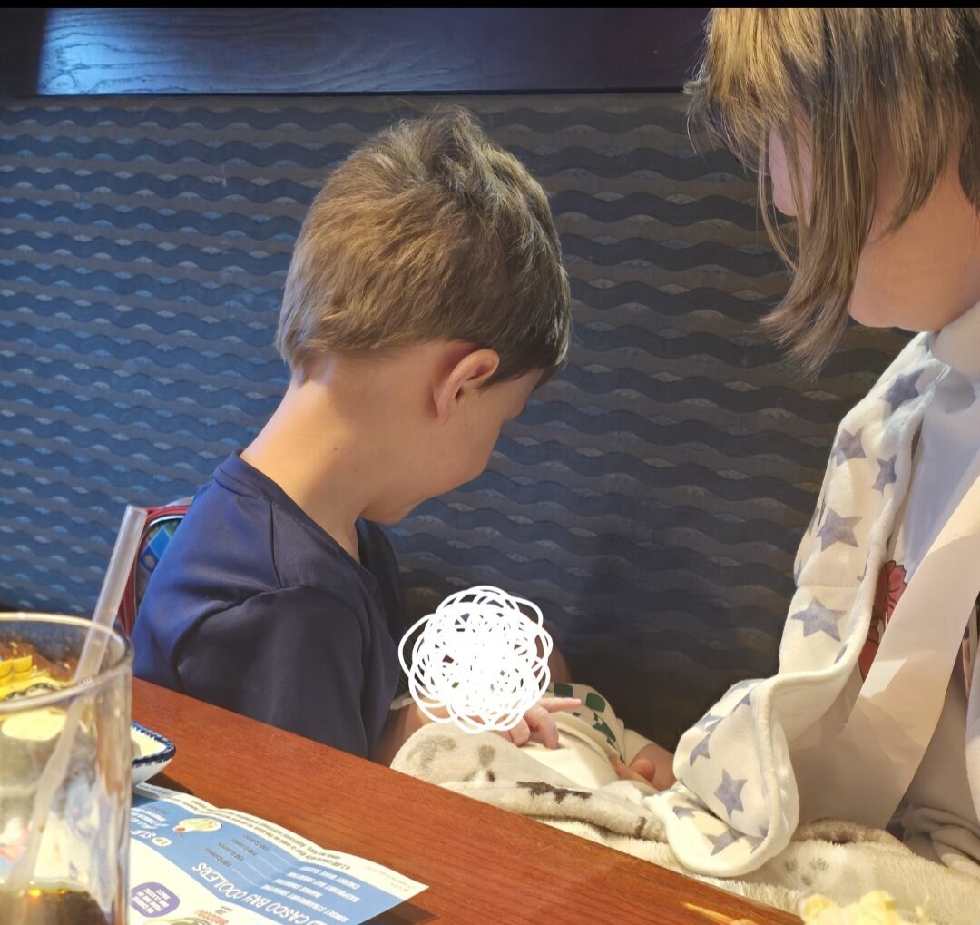 Little boy holding baby with woman watching over them