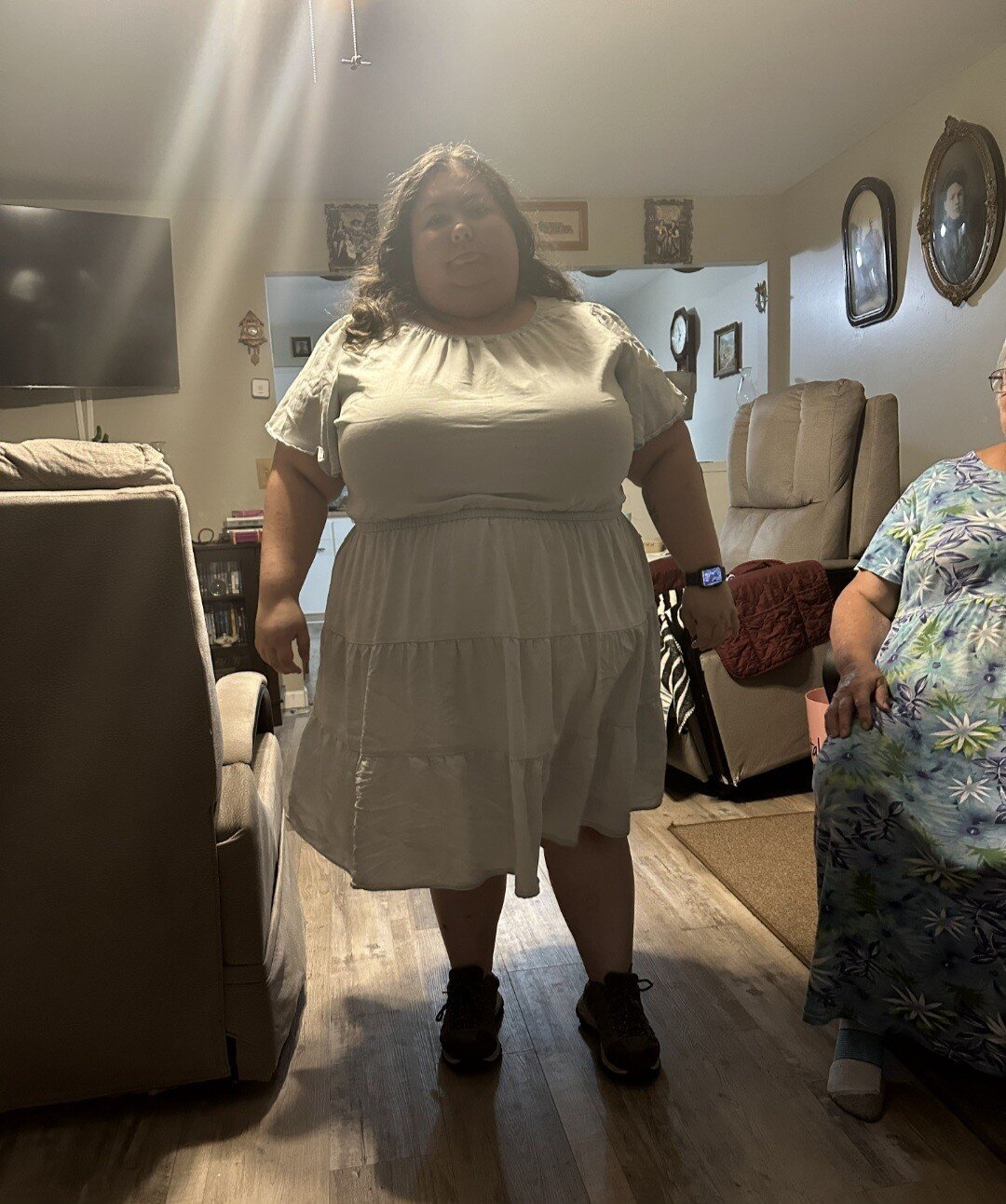 Woman in light blue dress standing in living room.(at 300lbs)