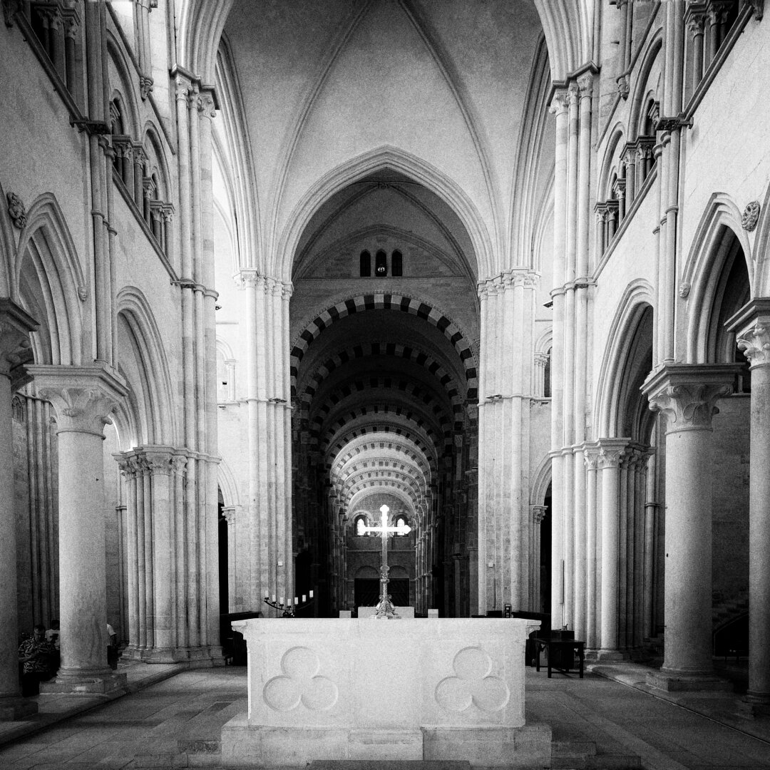 tha altar and nef and perspective of a massive basilica. the cross on the altar is very white and shiny