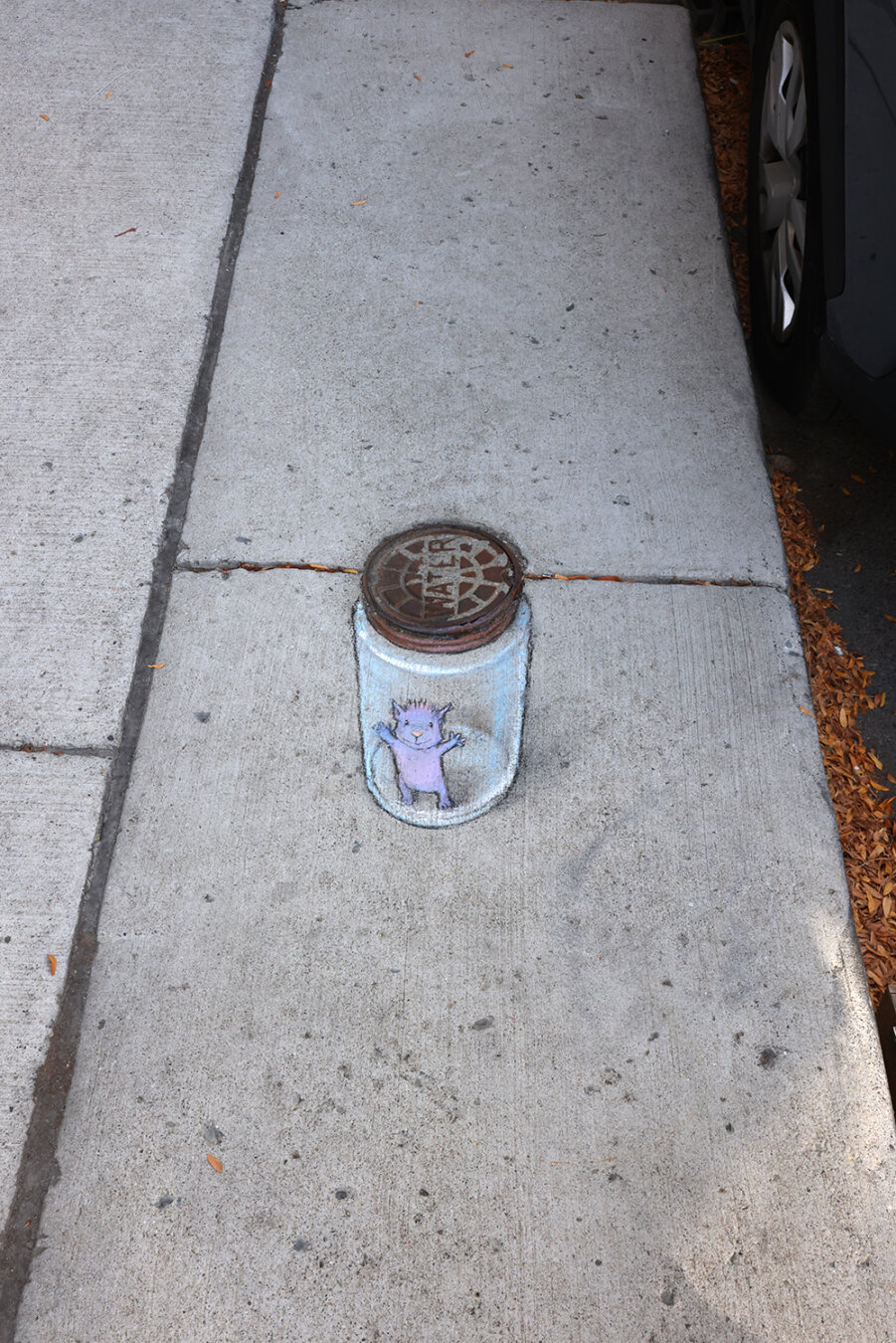 sidewalk chalk drawing of a small purple imp smiling and reaching out his arms from inside a glass jar, the lid of which is a utility cover set in the concrete