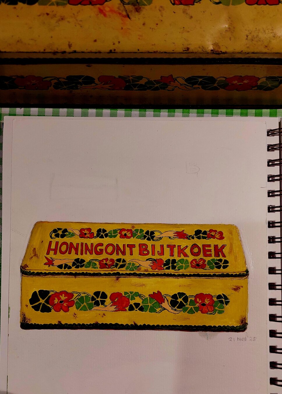 Yellow, oblong tin, painted with red, dark, and light green flowers. The lid is labeled "Honey Gingerbread" in red letters. Some rust spots here and there.