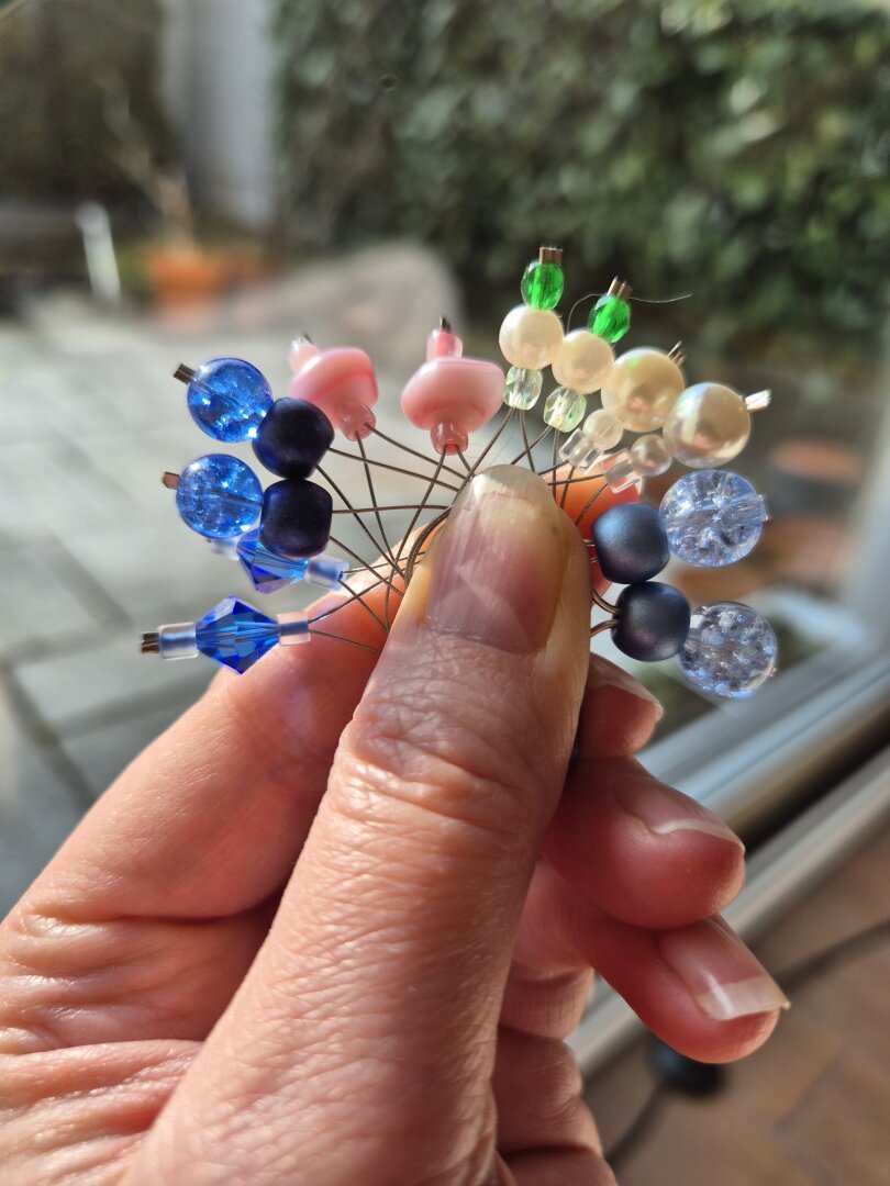 meine Hand hält 6 Paare Maschenmarkierer zwischen Daumen und Zeigefinger