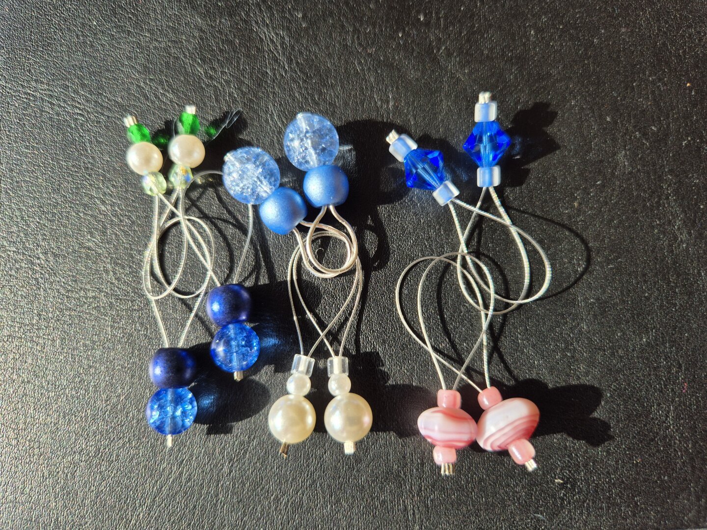 6 Paare Maschenmarkierer liegen auf einem schwarzen Untergrund