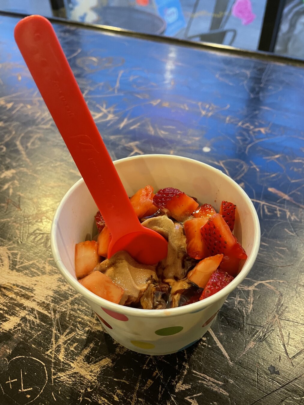 Chocolate frozen yogurt with peanut butter and strawberries in a cup.