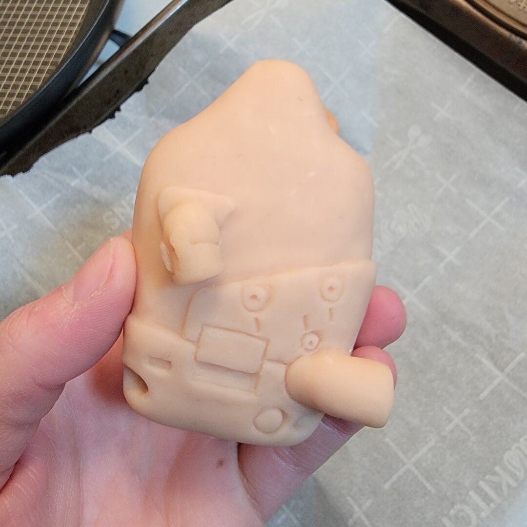 1 of 4 photos of a baked and unpainted clay figurine of the BB pod from Death Stranding, roughly 3" tall.