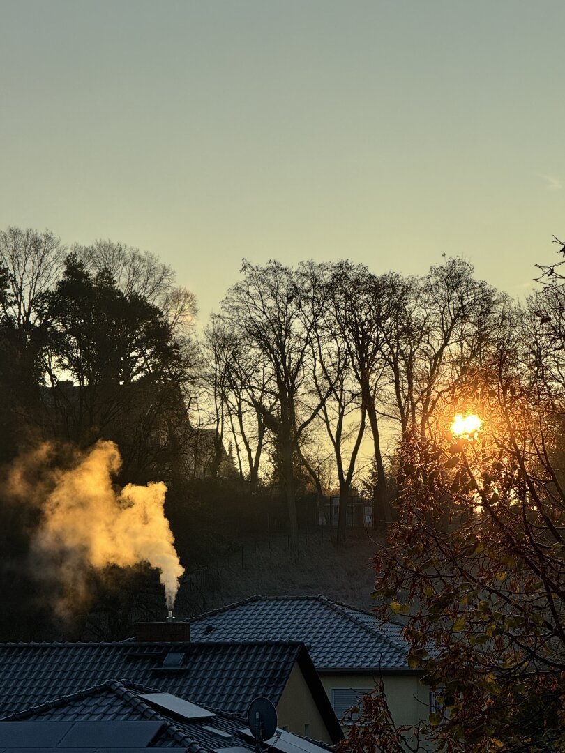 Sunrise over several roofs, chimney with smoke