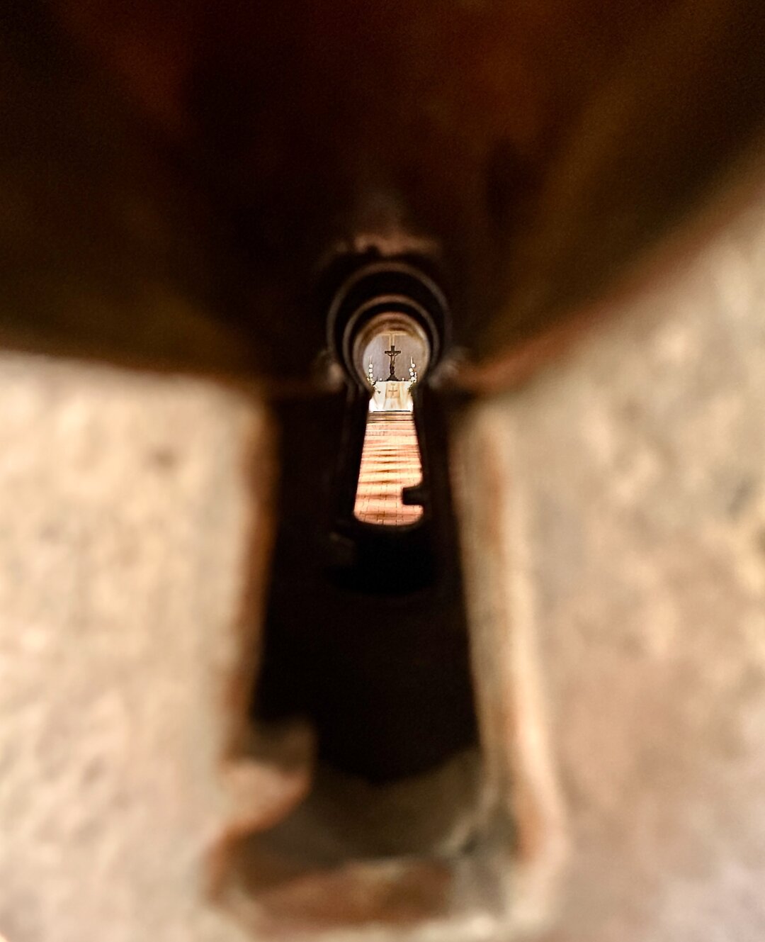 Looking through the keyhole you see the altar of the church in the distance.