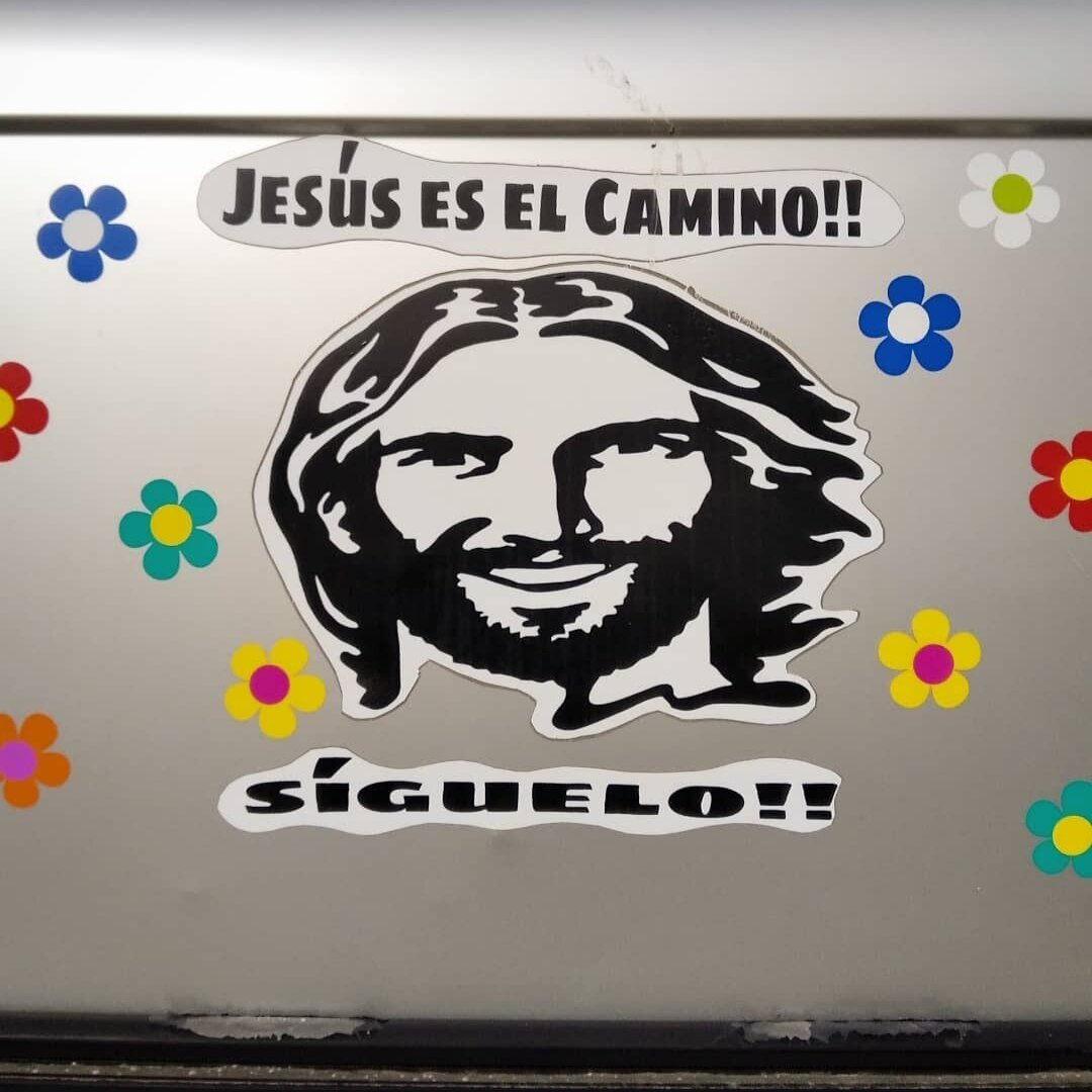 Pegatina de Jesús  con leyenda que dice "JESÚS ES EL CAMINO , SÍGUELO! " y muchas margaritas 

Jesús Stiker that says "Jesús is the way, follow It" and many daisys