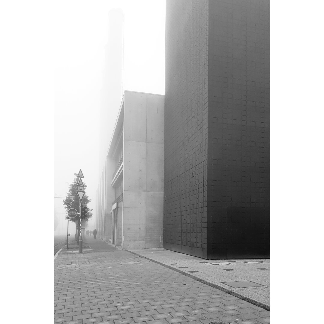 Misty weather on the Kirchberg only allows seeing a silhouette walking next to the brutalist buildings of Luxenergie