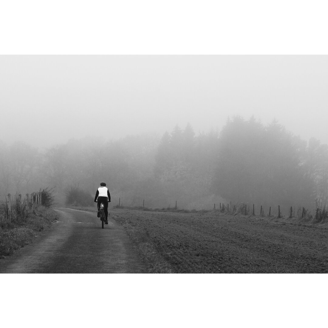 Blanck and white picture of a bike alone on a path in the foggy countryside around Leudelange