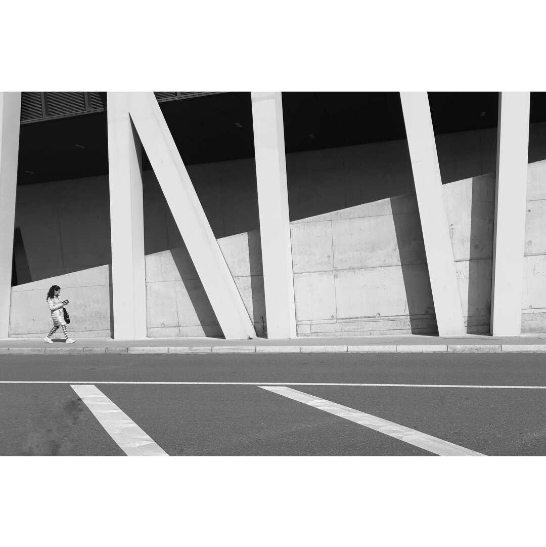 Black and white street photography taken in Luxembourg city showing a woman passing by the ramp of the Luxexpo parking lot.