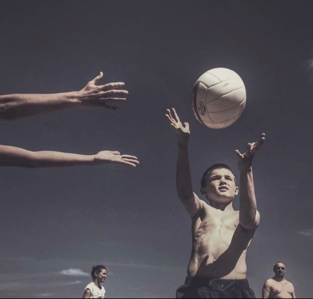 Photography. A color photo of a group of children playing ball. Two outstretched arms can be seen on the left against a gray sky, reaching towards a small boy with a naked upper body. The boy is holding both hands in the air to catch a white ball that is flying in front of him. The upper bodies of a man and a woman can be seen in the background.
Info: The Russian photographer Dmitri Markov died on February 16, 2024 at the age of 42, on the same day as Alexei Navalny. Markov, who photographed exclusively with an iPhone, became famous for his images of everyday life in Russia and its regions. His photo of a masked policeman sitting under a portrait of President Vladimir Putin became a symbol of the protests against the imprisonment of Kremlin critic Alexei Navalny in 2021. The photo was sold in an online auction for 2 million rubles (21,760 US dollars), with the proceeds going to people who were detained or fined during the rallies in support of Navalny. (Source: The Moscow Times)