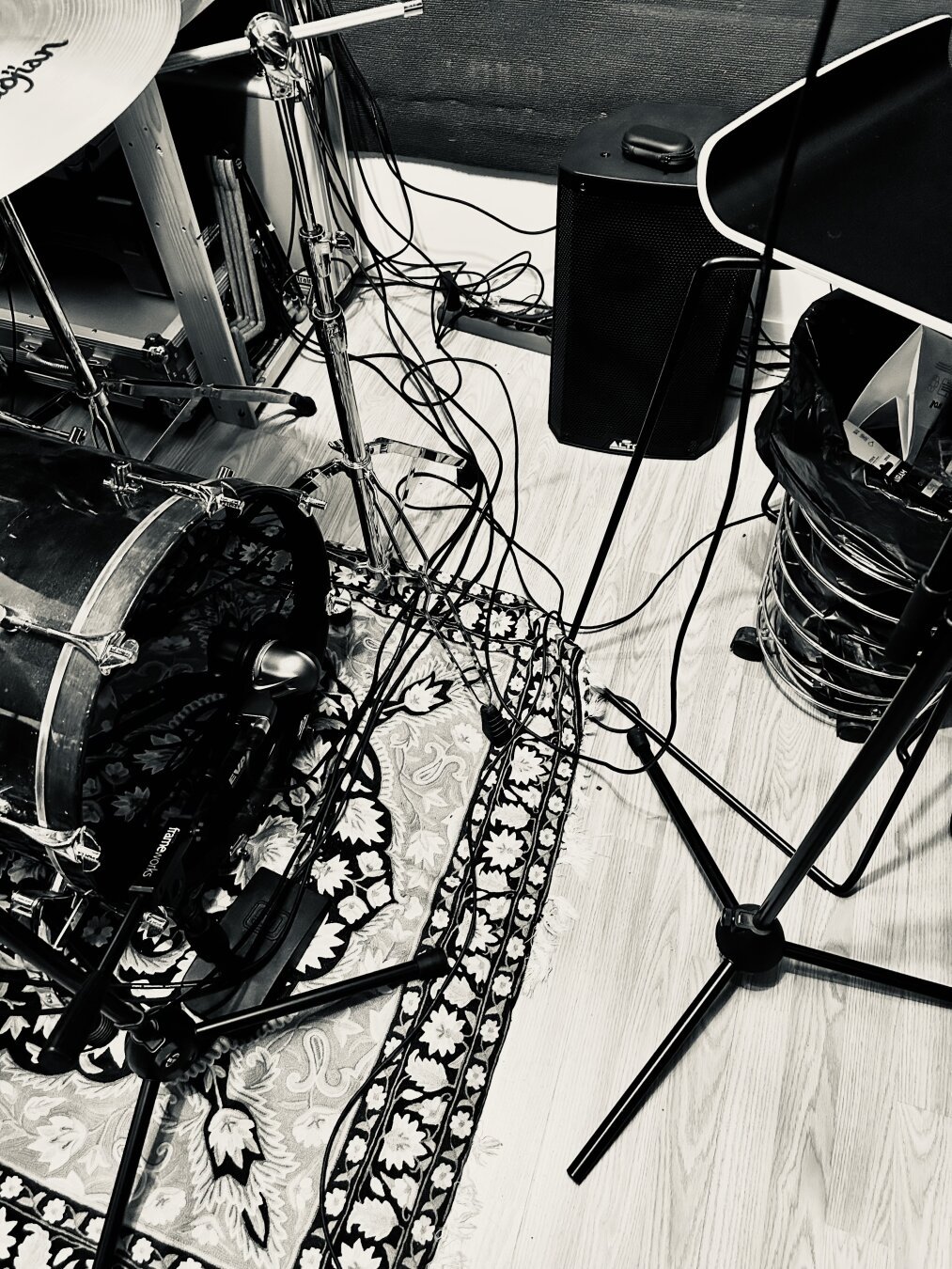Music equipment, with drums and cables on the floor next to a monitor