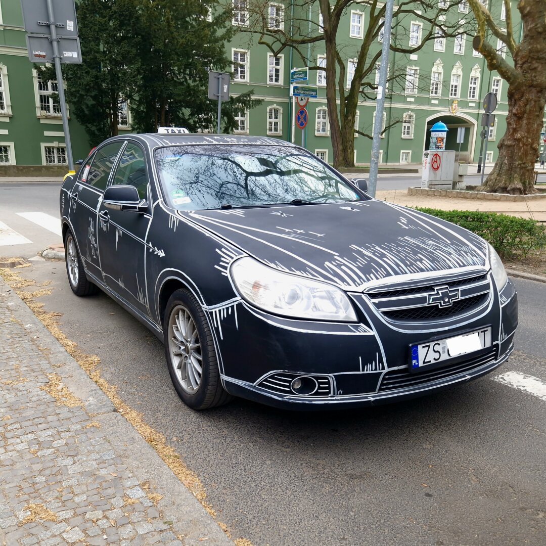 A TAXI car painted black with the white outlines. Looks like a car taken from a comic book.