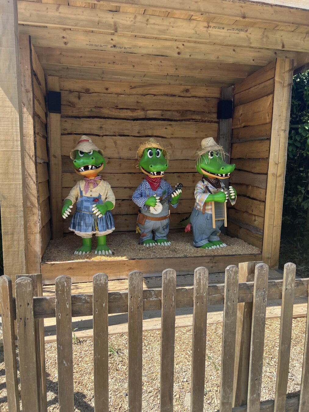 Three animatronic alligators dressed in classic hillbilly type getup holding instruments.