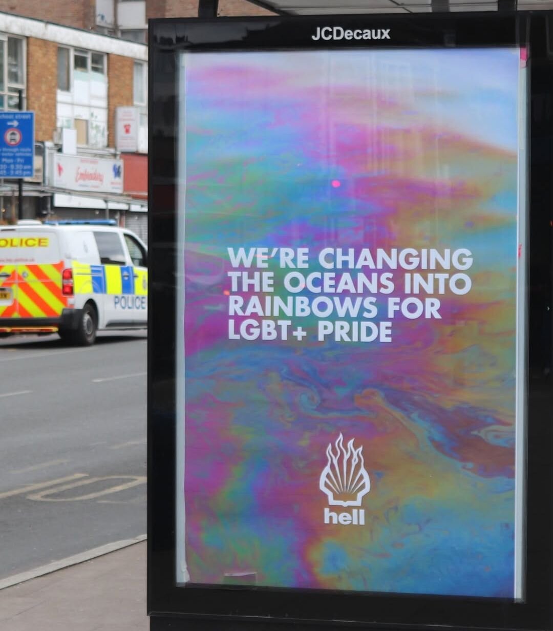 Adbusting campaign showing the Shell logo on fire, branded "hell", and a photo of water polluted with oil, captioned "We're changing the oceans into rainbows for LGBT+ Pride"