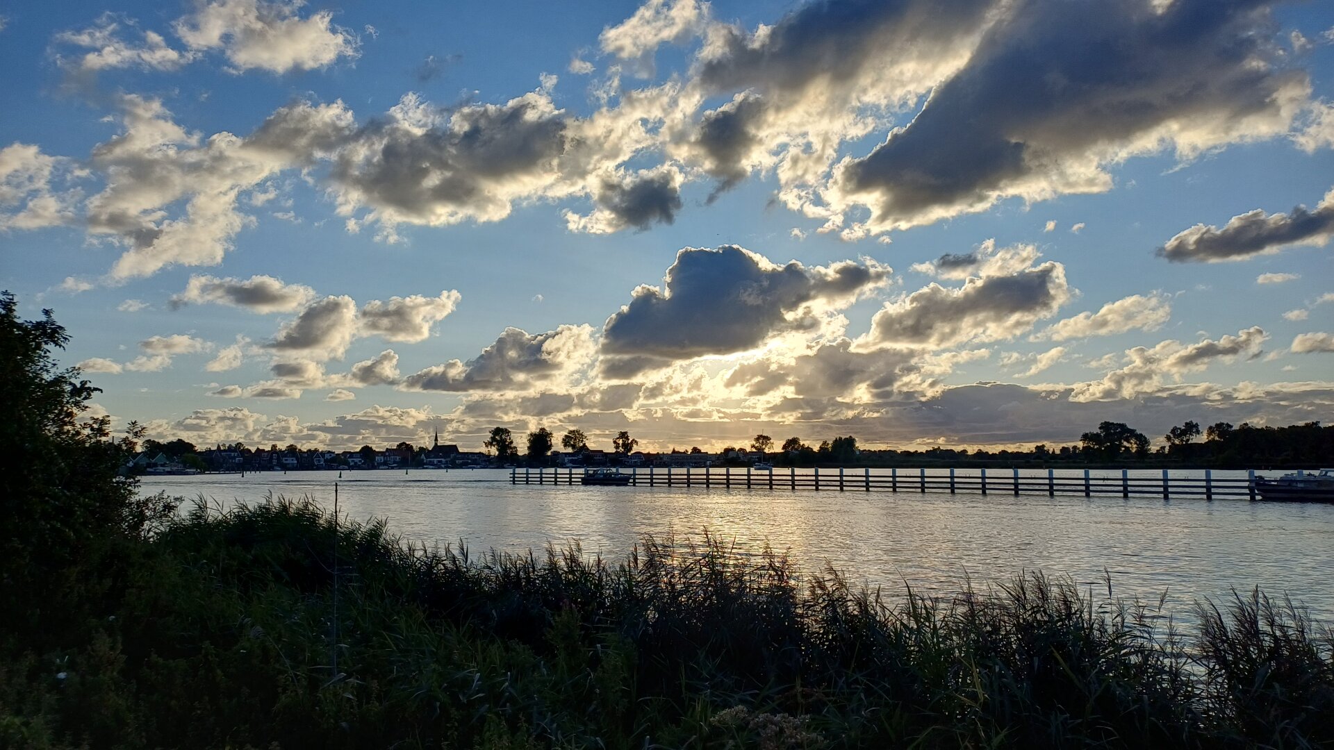 On the way back home, view across the river IJ  near Spaarndam with the sun behind a cloudy sky