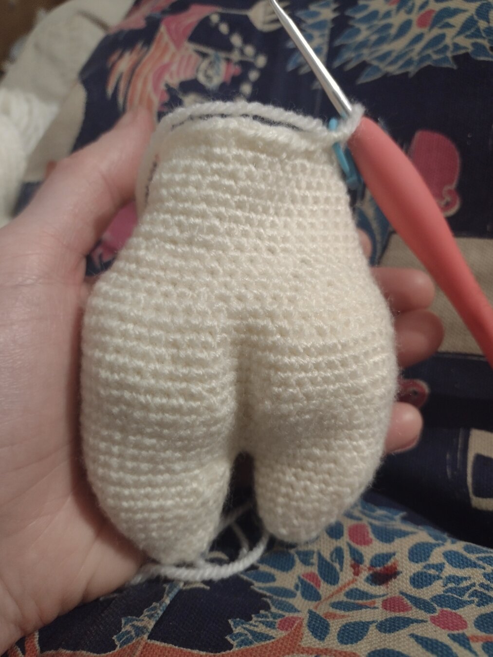 The back of a palm sized, half finished amigurumi. It has two dump legs, a pronounced bum and tapered waist.