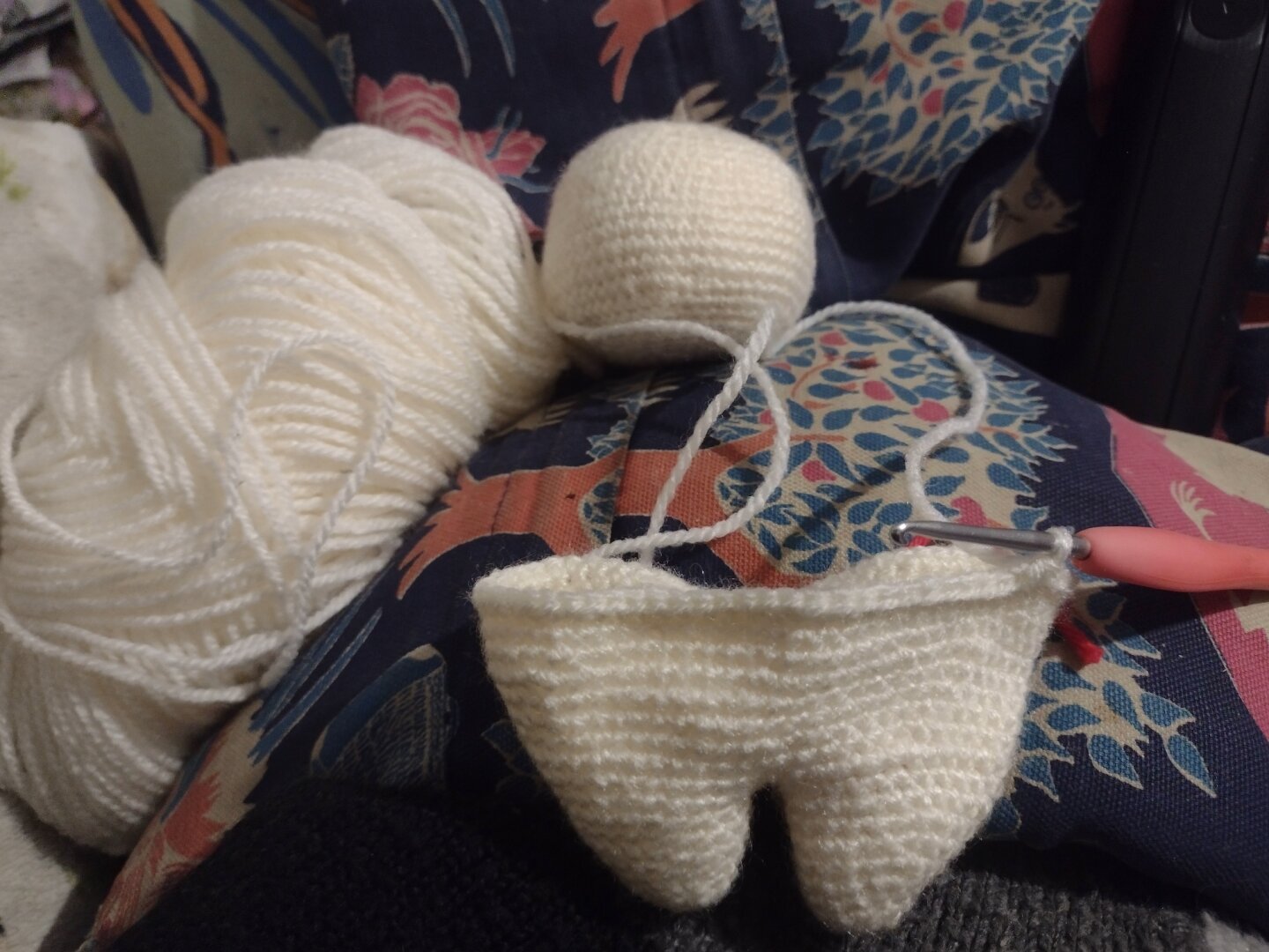 A loosely wound skein of cream coloured yarn, and an unfinished crochet doll. There's a slightly squashed ball for a head, and the body is just two dumpy legs and a wider waist.