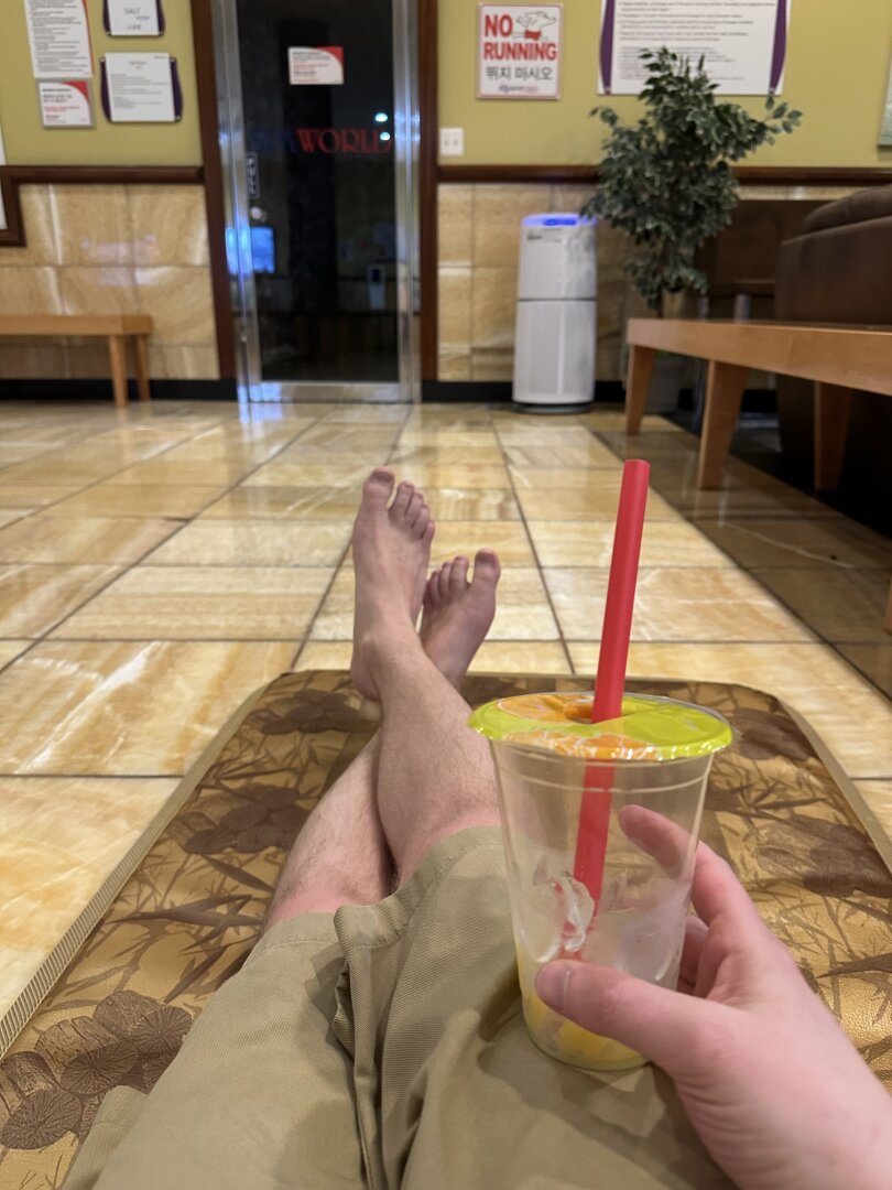 A photo of my crossed feet and my hand holding a cup of bubble tea