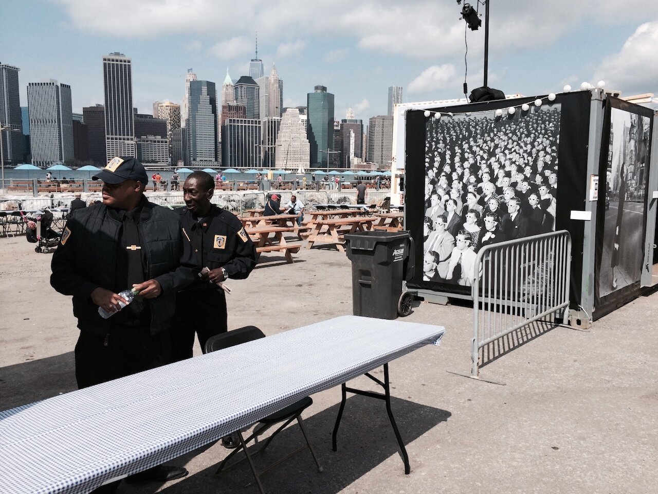 Title: Society Distracted by Off-Camera Spectacle

Alt Text: Photograph of two security guards looking off-camera to the left. To the right is a booth with a large Guy debord image on it. 

Photographer: Marshall Mayer aka @AuthenticPhoto

Date and Time: September 20, 2014 at 12:40 pm

Location: Photoville 2014, Brooklyn, NY  USA

License: CC BY-NC-ND 4.0

Caption: Where I went to school for a Master of Fine Arts, at the beginning of neoliberal America, some of the faculty and former students were heavily into the Frankfurt School and critical theory. I did not connect with them much at the time, photographically, but enough to recognize that I was a democratic socialist. Forty years later, I'm still trying to make sense of it all.

Hashtags: #CriticalTheory #Neoliberalism #FrankfurtSchool #Journalism #Spectacle #FakeNews #Situationists #Authentic #Photography

Source: https://take-note.com/note-takers/marshall--mayer/notes/society-distracted-by-off-camera-spectacle/view