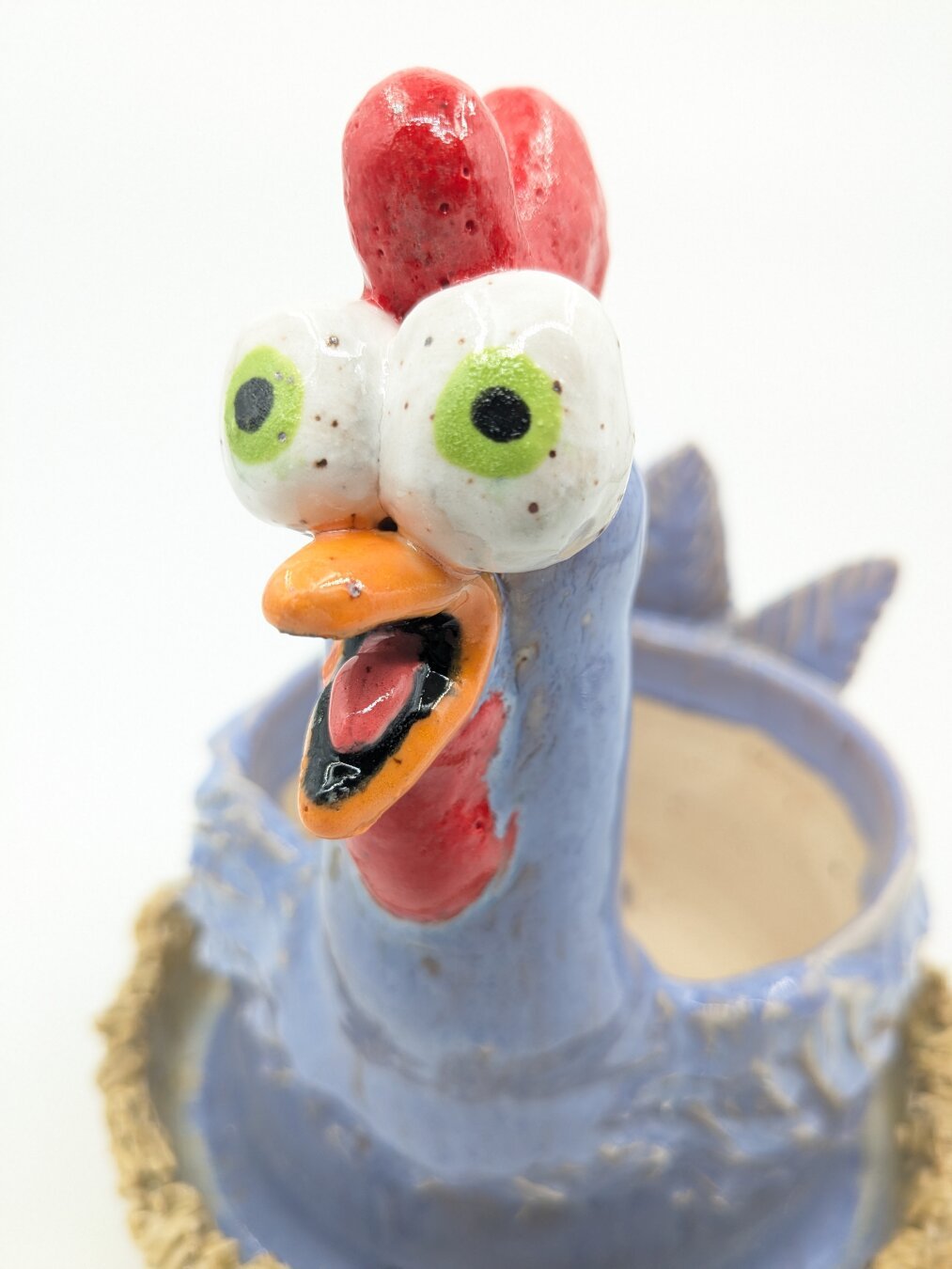 A purple ceramic funky chicken with bulging eyes is shown upclose