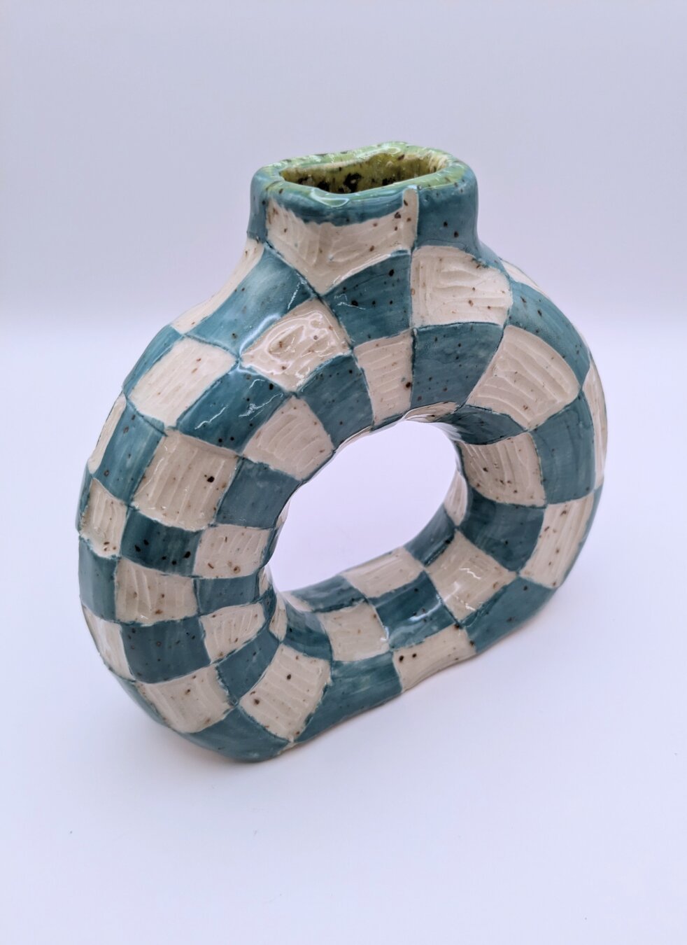 A handmade wheel thrown doughnut vase with checkered blue and white pattern