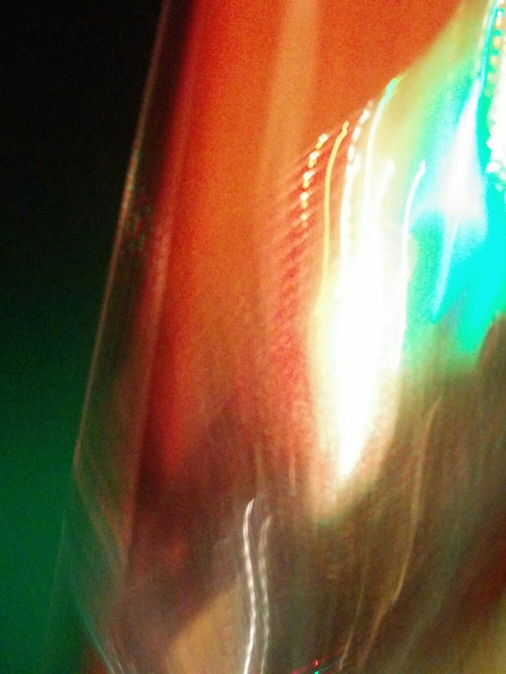 An abstract, blurry photograph showing distorted light leaks and motion blur in vivid colours of emerald green, vibrant red, bright white, and turquoise green.