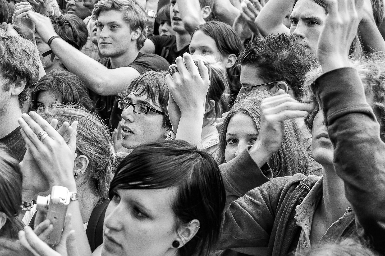 Une foule de personnes. Elles regardent toutes sur la gauche. Seule une personne, dont on n'aperçoit que les yeux, regarde vers l'appareil-photo.