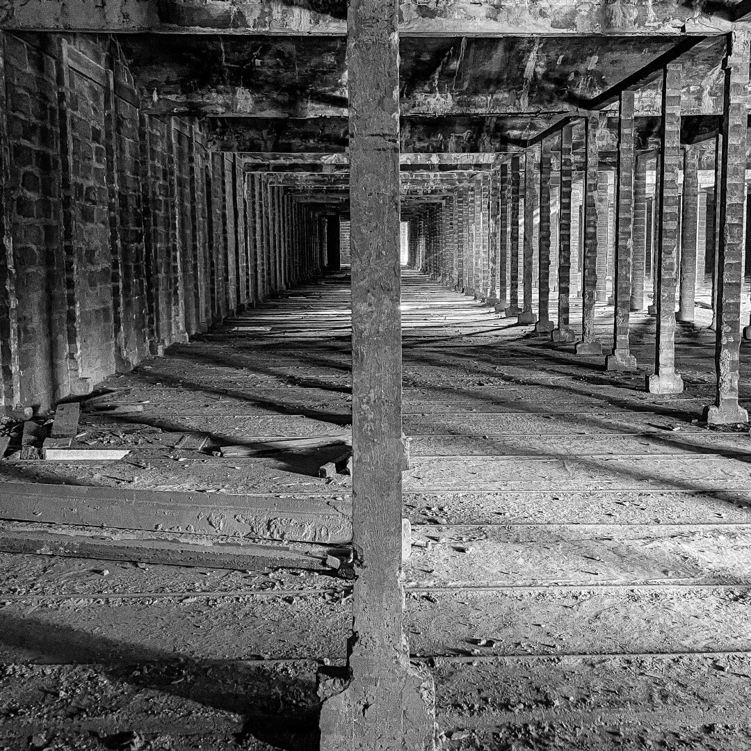 Un bâtiment abandonné. Au premier plan et au milieu de la photo, un poteau. En arrière-plan, les autres poteaux qui soutiennent la toiture.