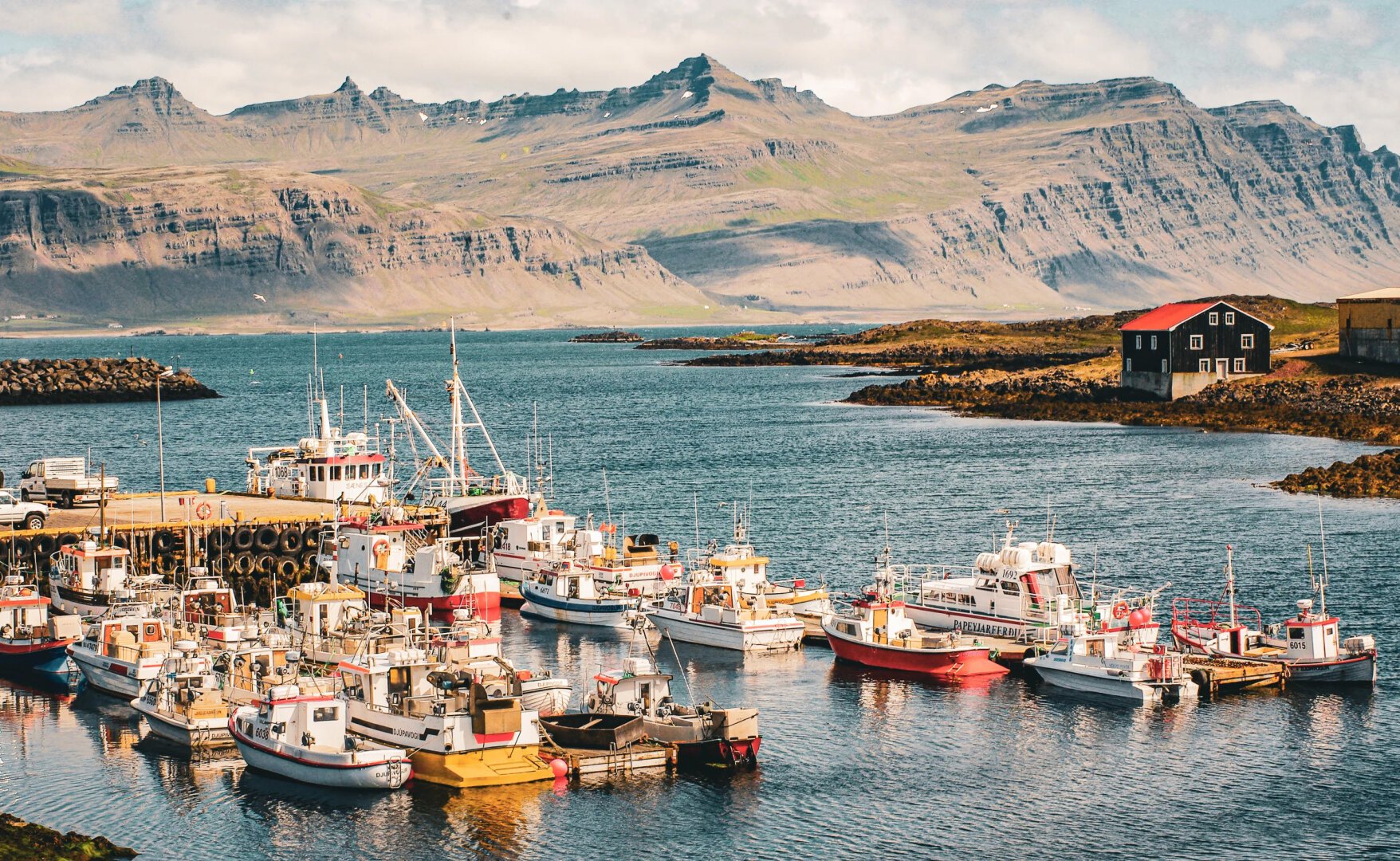 Des bateaux dans un port. Derrière eux, des montagnes.