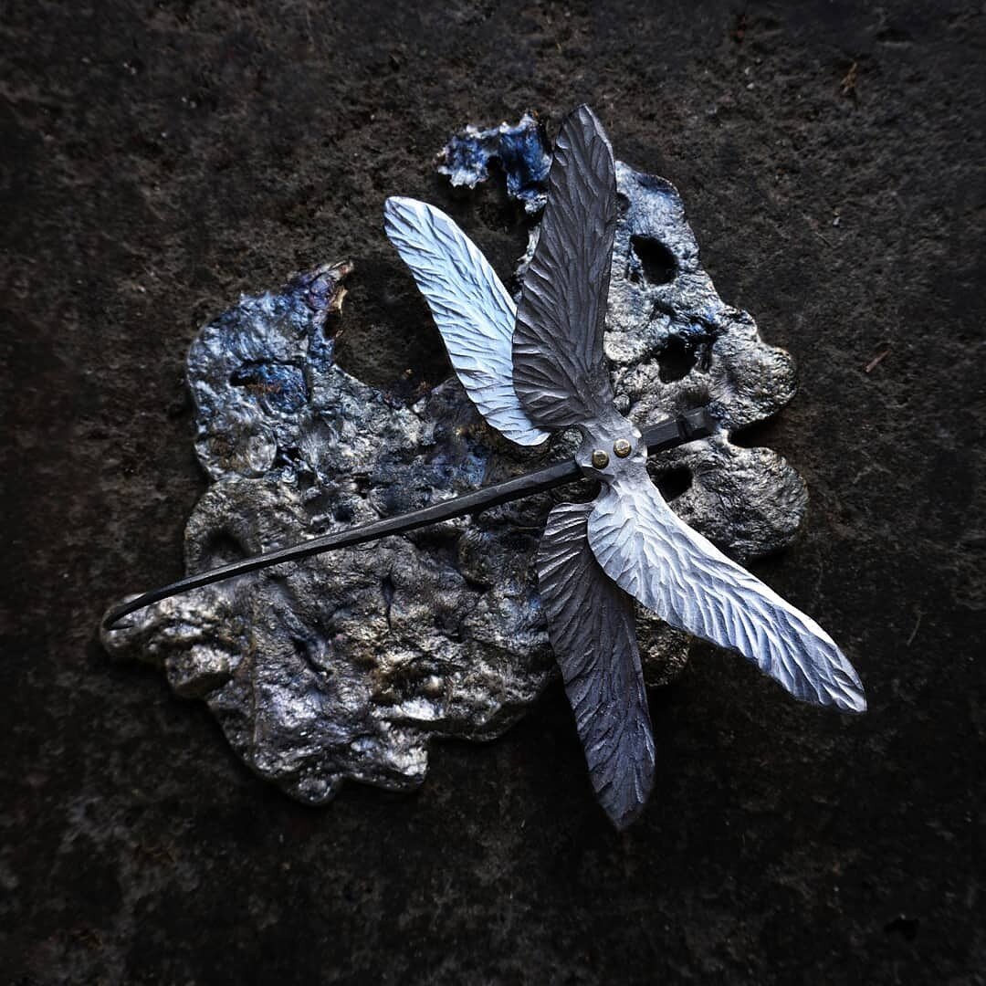 Photo of a hand forged dragonfly with shiny steel wings, mounted on a foot of casted brass.