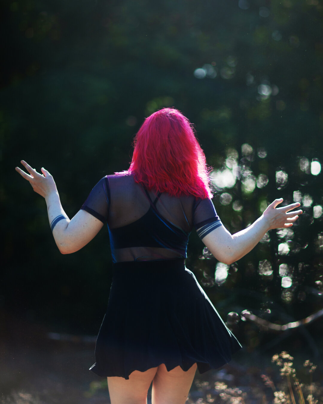 A photo of a woman dancing in a forest by the sea