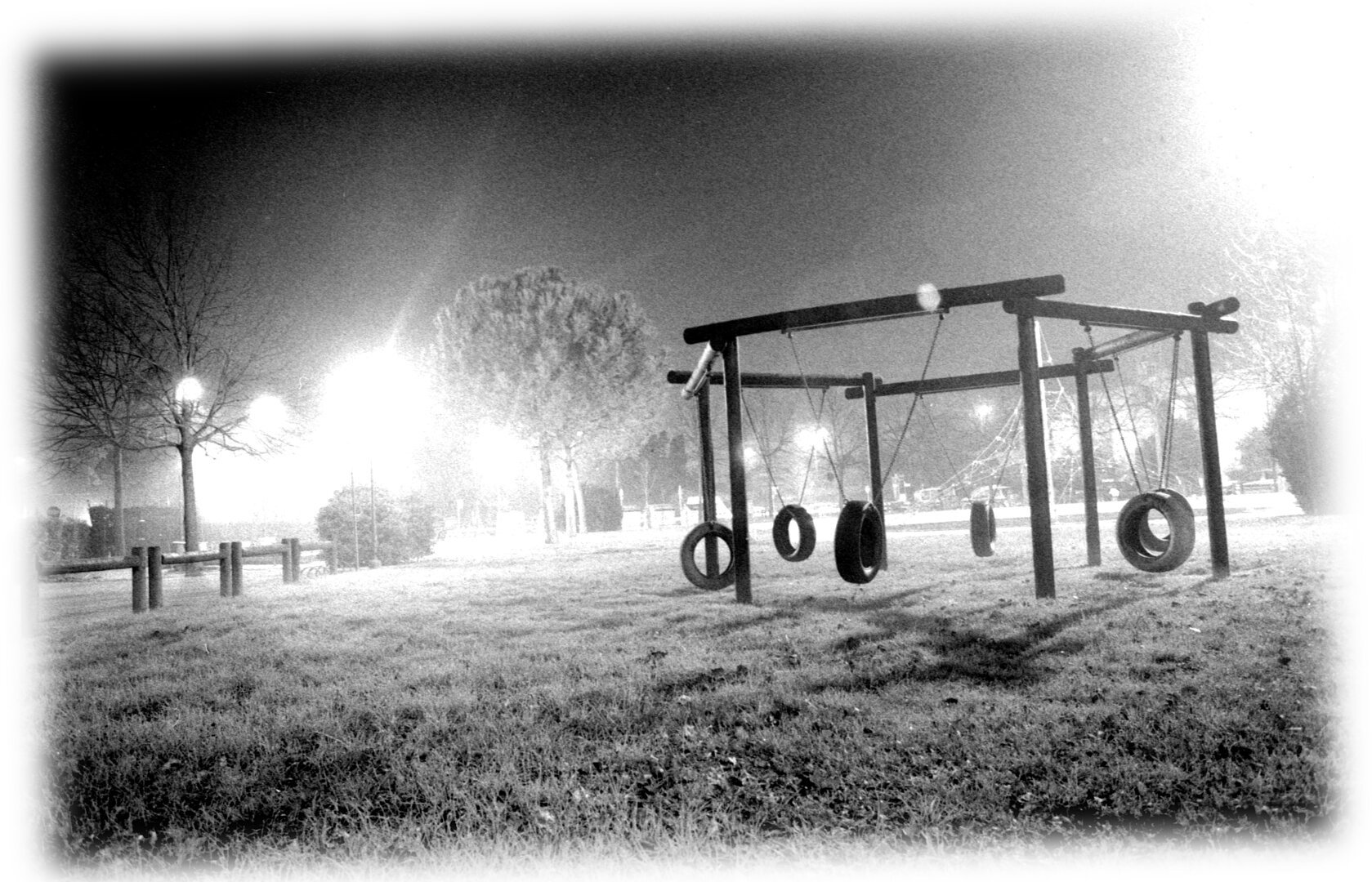 black and white picture of a foggy playground at night