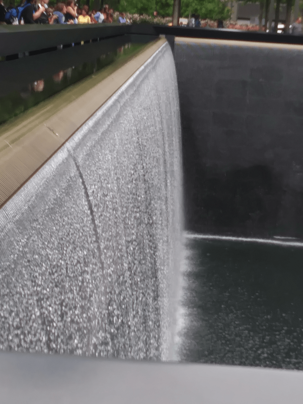 Water streaming down the side of one of the memorial pools
