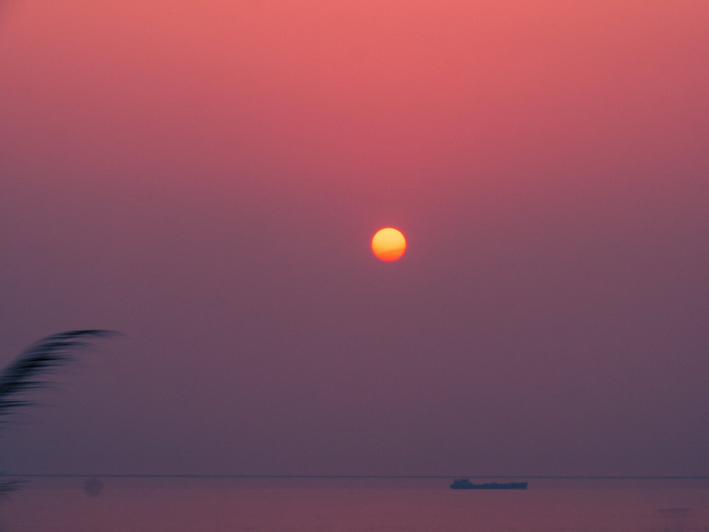 Purple and red sunset with a boat in the distance