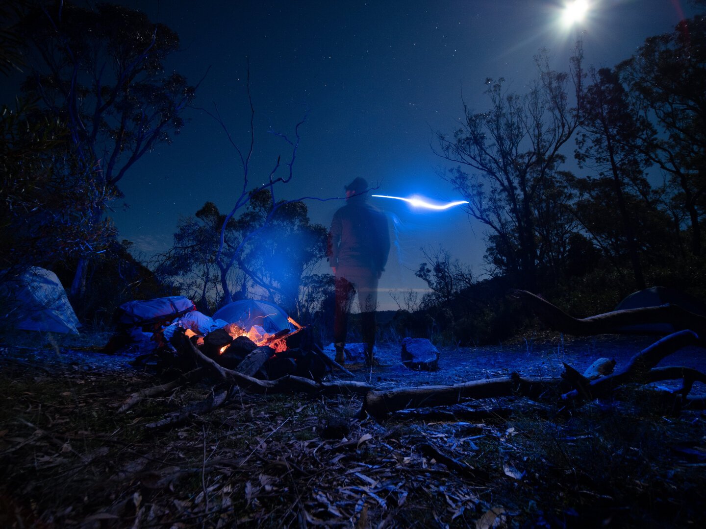 Long exposure of a man by a campfire at night with his back to camera