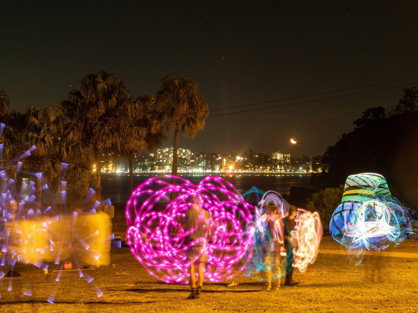 Shot at Shelley Beach in Sydney at night, people twirl lights in a long exposure