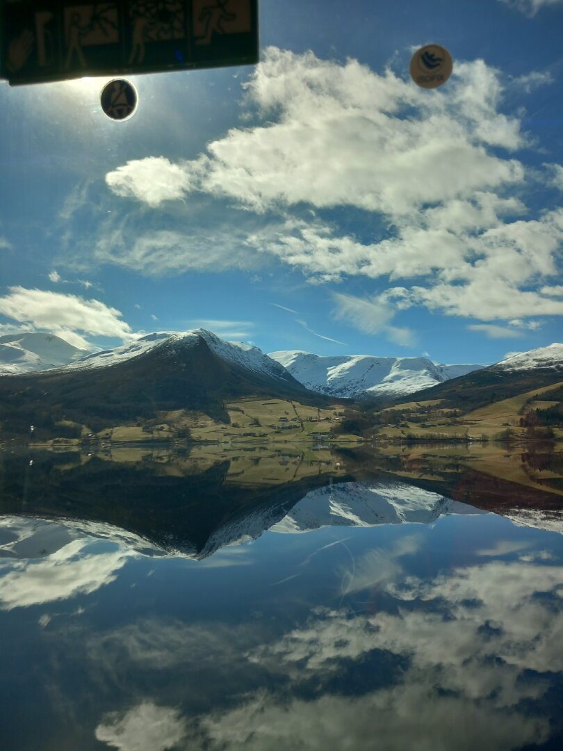 Mountains reflecting the water. And a piece of the bus window.