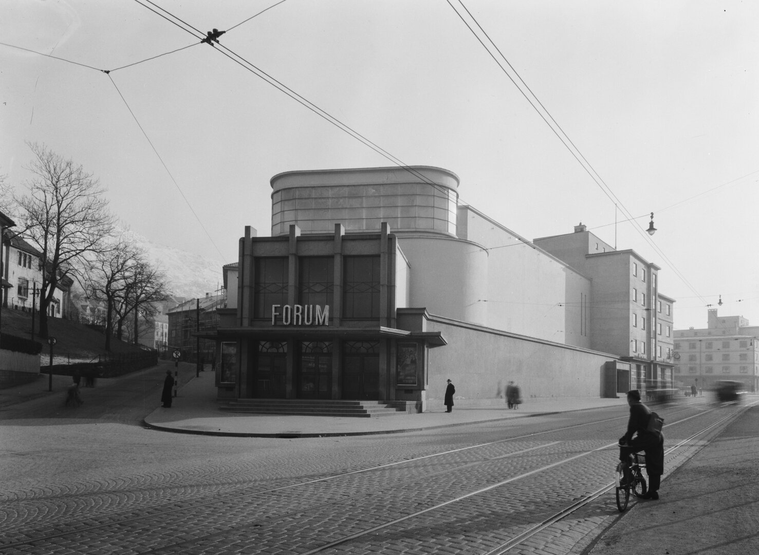 A black and white photo of a majestic art deco building with clean lines, leading down to a entrance where the marquee reads 